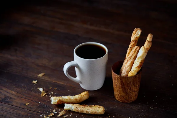 Taza de café y palitos de pan sobre un viejo fondo de madera, primer plano, enfoque selectivo . — Foto de Stock