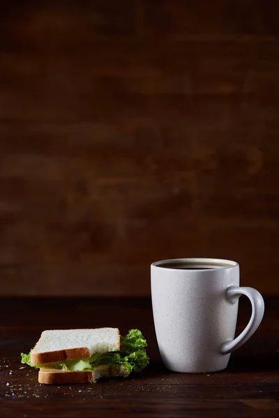 Table de petit déjeuner avec sandwich et café noir sur fond bois rustique, gros plan, mise au point sélective — Photo