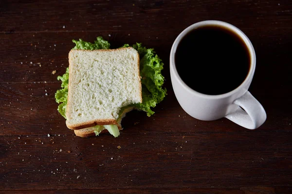 Πρωινό τραπέζι με σάντουιτς και μαύρο καφέ ρουστίκ ξύλινα φόντο, γκρο πλαν, επιλεκτική εστίαση — Φωτογραφία Αρχείου