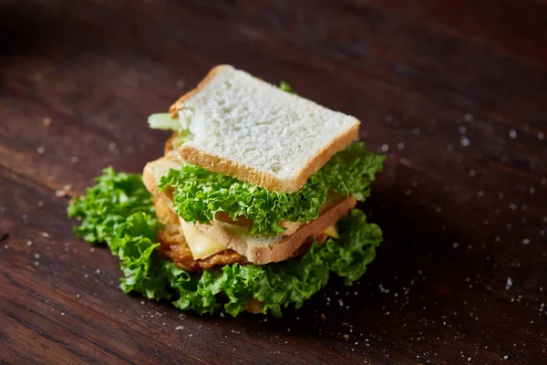 Sándwiches sabrosos y frescos en la tabla de cortar sobre un fondo de madera oscura, primer plano —  Fotos de Stock