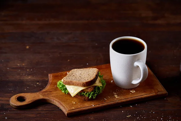 Table de petit déjeuner avec sandwich et café noir sur fond bois rustique, gros plan, mise au point sélective — Photo