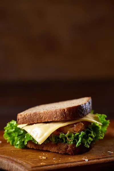 Sándwiches sabrosos y frescos en la tabla de cortar sobre un fondo de madera oscura, primer plano —  Fotos de Stock