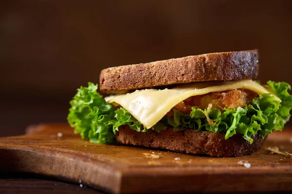 Lezzetli ve taze sandviç kesme tahtası üzerinde bir koyu ahşap arka plan üzerinde yakın çekim