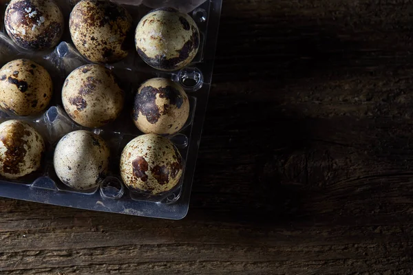 Bıldırcın yumurtası koyu ahşap arka plan, üstten görünüm, seçici odak plastik bir kap içinde