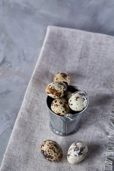 Küçük dekoratif kova peçete bıldırcın yumurtalarının dolu beyaz dokulu arka plan, yakın çekim, seçici odak üzerinde.
