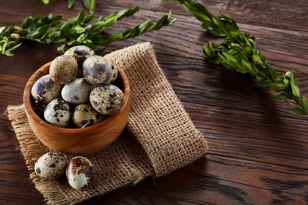 Kom met eieren kwartel, eieren op een homespun servet, buxus op houten achtergrond, close-up, selectieve aandacht — Stockfoto