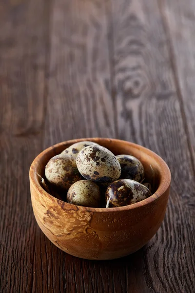 Bir koyu ahşap arka plan, üstten görünüm, yakın çekim bir ahşap kase taze bıldırcın yumurtası