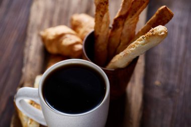 Kahve fincanı, breadsticks ve kruvasan bir eski ahşap arka plan, yakın çekim, seçici odak.