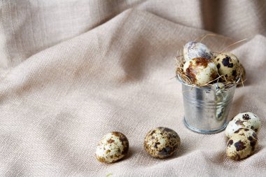 Küçük dekoratif kova peçete bıldırcın yumurtalarının dolu beyaz dokulu arka plan, yakın çekim, seçici odak üzerinde.