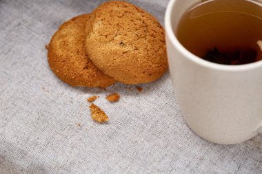 Beyaz porselen kupa çay ve tatlı kurabiye beyaz arka plan, üstten görünüm, seçici odak saf peçete üzerinde
