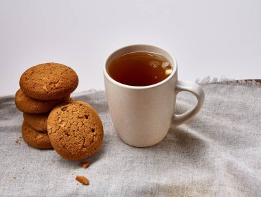 Beyaz porselen kupa çay ve tatlı kurabiye beyaz arka plan, üstten görünüm, seçici odak saf peçete üzerinde