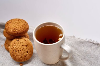 Beyaz porselen kupa çay ve tatlı kurabiye beyaz arka plan, üstten görünüm, seçici odak saf peçete üzerinde