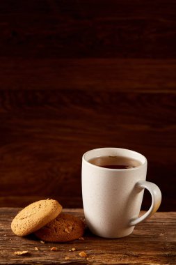 Ahşap ahşap arka plan, üstten görünüm, seçici odak parçası üzerinde çay ve tatlı kurabiye beyaz porselen kupa