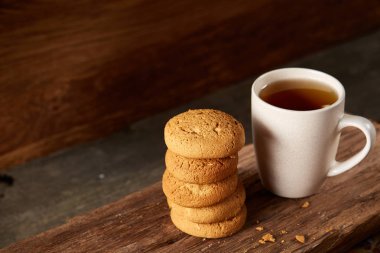Ahşap ahşap arka plan, üstten görünüm, seçici odak parçası üzerinde çay ve tatlı kurabiye beyaz porselen kupa