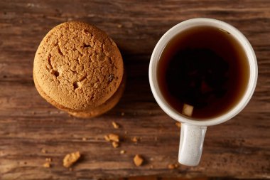 Ahşap ahşap arka plan, üstten görünüm, seçici odak parçası üzerinde çay ve tatlı kurabiye beyaz porselen kupa