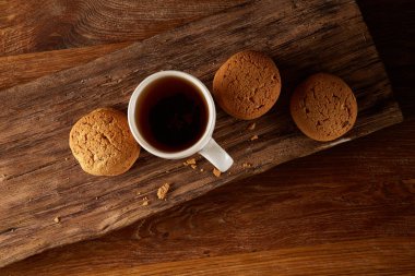 Ahşap ahşap arka plan, üstten görünüm, seçici odak parçası üzerinde çay ve tatlı kurabiye beyaz porselen kupa