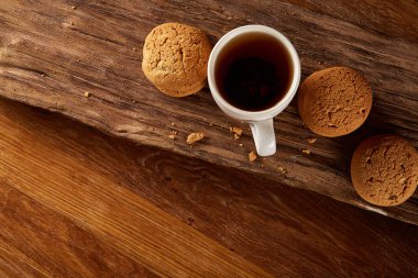 Ahşap ahşap arka plan, üstten görünüm, seçici odak parçası üzerinde çay ve tatlı kurabiye beyaz porselen kupa