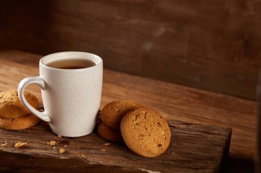 Ahşap ahşap arka plan, üstten görünüm, seçici odak parçası üzerinde çay ve tatlı kurabiye beyaz porselen kupa