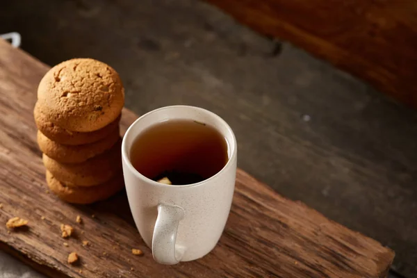 Taza de porcelana blanca de té y galletas dulces en pieza de madera sobre fondo de madera, vista superior, enfoque selectivo — Foto de Stock