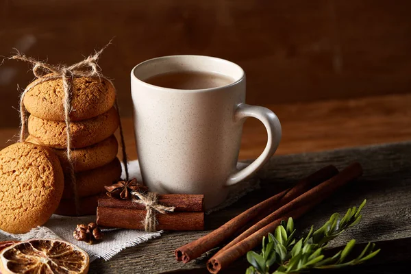 Tradizionale concetto di tè natalizio con una tazza di tè caldo, biscotti e decorazioni su un tavolo di legno, focus selettivo — Foto Stock