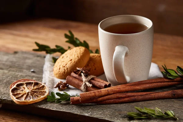 Concepto tradicional de té de Navidad con una taza de té caliente, galletas y decoraciones en una mesa de madera, enfoque selectivo —  Fotos de Stock