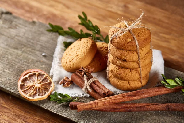 Composición navideña con pila de galletas, canela y naranjas secas sobre fondo de madera claro, primer plano . —  Fotos de Stock