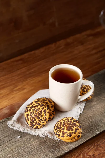 Cup of tea and chocolate chip cookies on white homespun napkin in country style, selective focus. — Stock Photo, Image