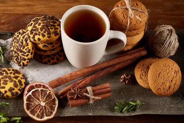 Concepto tradicional de té de Navidad con una taza de té caliente, galletas y decoraciones en una mesa de madera, enfoque selectivo —  Fotos de Stock