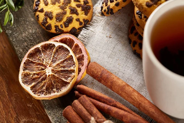 Concepto tradicional de té de Navidad con una taza de té caliente, galletas y decoraciones en una mesa de madera, enfoque selectivo —  Fotos de Stock