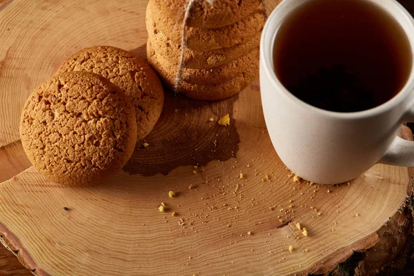 Chávena branca de chá e biscoitos em um log sobre fundo de madeira estilo country, close-up, foco seletivo — Fotografia de Stock