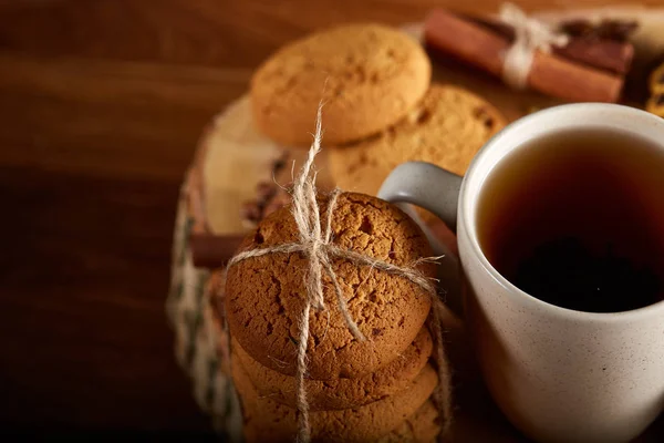 Concepto de Navidad con una taza de té caliente, galletas y decoraciones en un registro sobre fondo de madera, enfoque selectivo —  Fotos de Stock