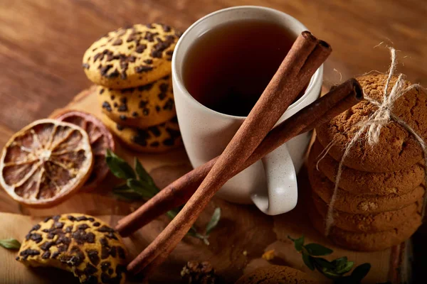Concepto de Navidad con una taza de té caliente, galletas y decoraciones en un registro sobre fondo de madera, enfoque selectivo —  Fotos de Stock