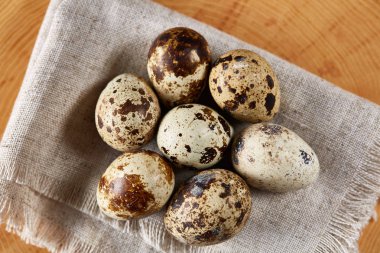 Bir günlük bir peçeteye yuvarlağına düzenlenmiş ahşap arka plan, yakın çekim, seçici odak bıldırcın yumurtası.