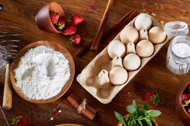 Top çilekli pasta ya da kek üzerine ahşap masa, düz yatıyordu yemek pişirmek için ham maddeler görüntüleyin. Fırın arka plan.