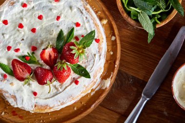 Çilek ve rustik ahşap zemin, seçici odak üzerine nane yaprakları ile süslenmiş krem şanti ile tart