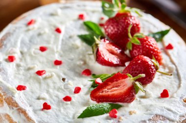 Çilek ve rustik ahşap zemin, seçici odak üzerine nane yaprakları ile süslenmiş krem şanti ile tart