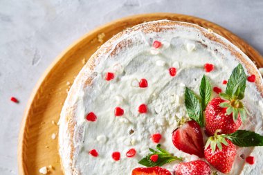 Çilek ve beyaz dokulu arka planda, seçici odak nane yaprakları ile süslenmiş krem şanti ile tart