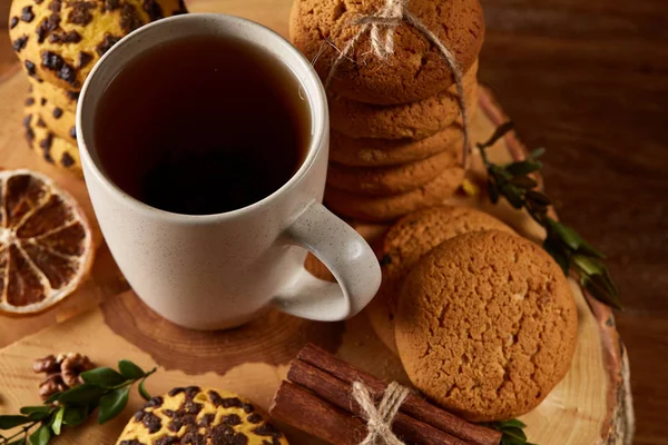 Conceito de Natal com uma xícara de chá quente, biscoitos e decorações em um log sobre fundo de madeira, foco seletivo — Fotografia de Stock