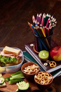 Okul öğle yemeği molası ile sağlıklı öğle yemeği kutusu ve okul malzemeleri ahşap masa, seçici odak kavramı.