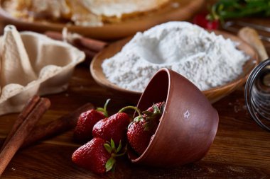 Pişirme arka plan, yakın çekim, seçici odak üzerinde devrilmiş bir kase kırmızı taze çilek.