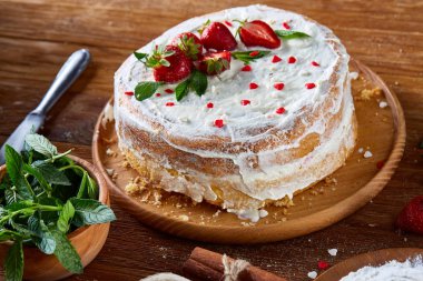 Çilekli tart ahşap arka plan üzerinde düz yatıyordu organik maddeler tarafından çevrili ekşi krem şanti ile kaplı.