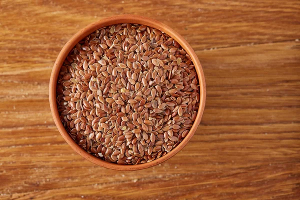 Keten tohumu rustik ahşap arka plan, seçici odak üzerinde ahşap kase üzerinde üstten görünüm.