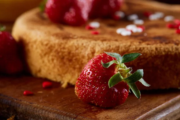 Gâteau fait maison avec des fraises biologiques fraîches sur planche à découper sur fond en bois, faible profondeur de champ . — Photo