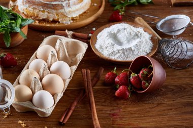 Top çilekli pasta ya da kek üzerine ahşap masa, düz yatıyordu yemek pişirmek için ham maddeler görüntüleyin. Fırın arka plan.