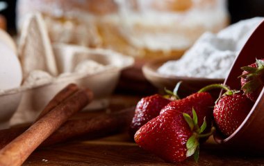 Pişirme arka plan, yakın çekim, sığ derinlik-in tarla üzerine devrilmiş bir kase kırmızı taze çilek.