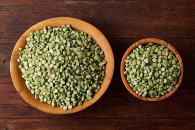 Bir kase ve plaka rustik ahşap arka plan, yakın çekim, üstten görünüm seçici odak üzerinde Besleyici yeşil bezelye.