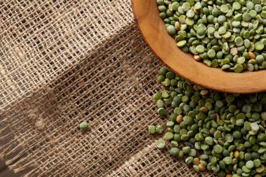 Çuval bezi masa örtüsü, yakın çekim, seçici odak, üstten görünüm ahşap bir plaka üzerinde ham yeşil bezelye.