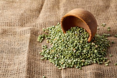 Çuval bezi masa örtüsü, yakın çekim, en iyi görünüm, seçici odak yeşil bezelye ile devrilmiş bir kase.