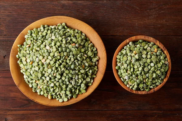 Bir kase ve plaka rustik ahşap arka plan, yakın çekim, üstten görünüm seçici odak üzerinde Besleyici yeşil bezelye.