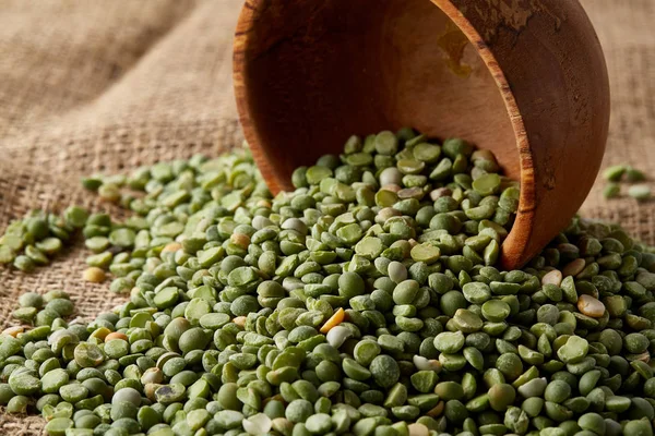 Çuval bezi masa örtüsü, yakın çekim, en iyi görünüm, seçici odak, sığ derinlik-in tarla yeşil bezelye ile devrilmiş bir kase.